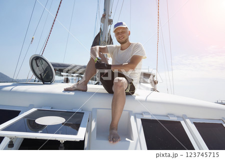 A man is calmly sitting on the deck of a beautiful sailboat 123745715