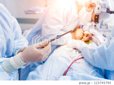 Spinal surgery. Surgeon show polyaxial screw in operating room Spinal surgery. Surgeon show polyaxial screw in operating room 123745795