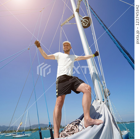 Male captain stands proudly on a sailboat enjoying the moment 123745842