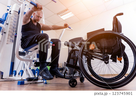 Disabled man doing strength exercises separate from the wheelchair. 123745901