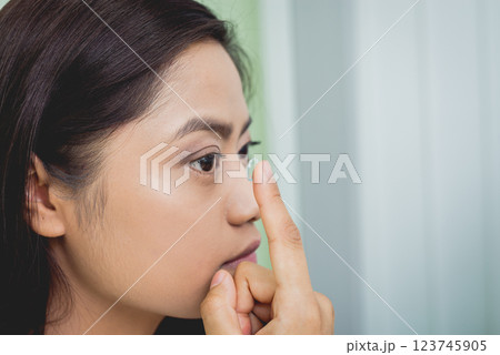 Young asian woman putting contact lens in right eye. 123745905