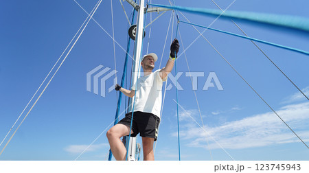 Male captain stands proudly on a sailboat enjoying the moment 123745943