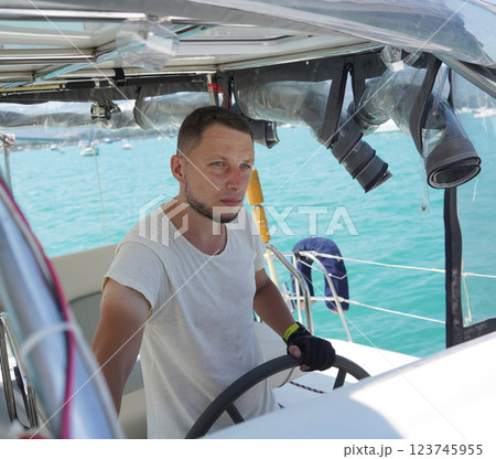 Young male captain in black gloves steering voyage boat Young male captain in black gloves steering voyage boat 123745955