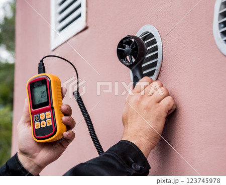 Technician use hand-held anemometer measuring air flowing measurement Technician use hand-held anemometer measuring air flowing measurement 123745978