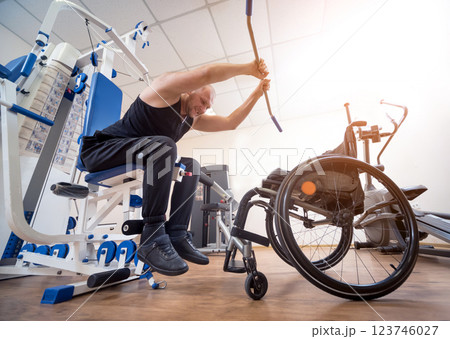 Disabled man doing strength exercises separate from the wheelchair. 123746027