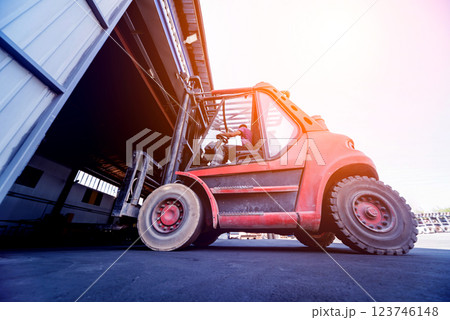 The big industrial forklift drives into the warehouse. 123746148