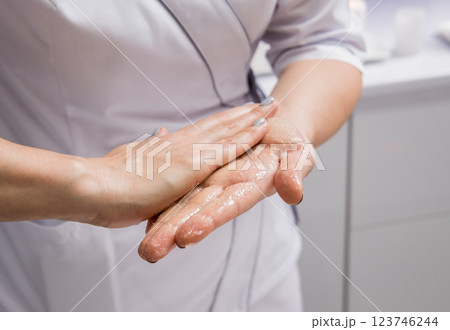 Masseur putting aroma oil on her hands, preparing for massage in spa center Masseur putting aroma oil on her hands, preparing for massage in spa center 123746244