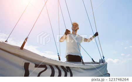 Male captain on deck of sailboat unpacking sails pulling zipper Male captain on deck of sailboat unpacking sails pulling zipper 123746264