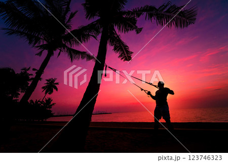 The athlete performs exercises on the beach with fitness straps 123746323