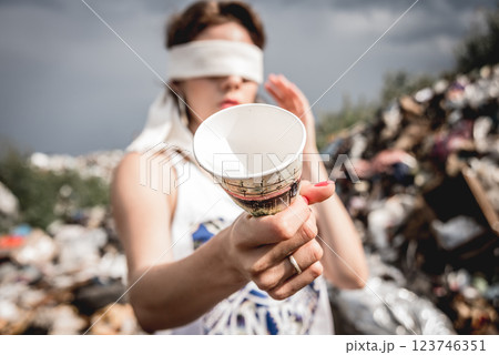 Blindfolded female volunteer in a landfill of plastic trash. 123746351
