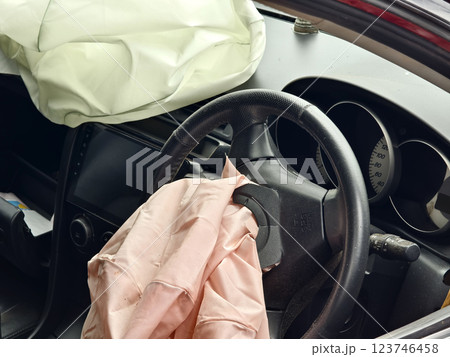 Airbag is currently hanging from the steering wheel of a car  123746458