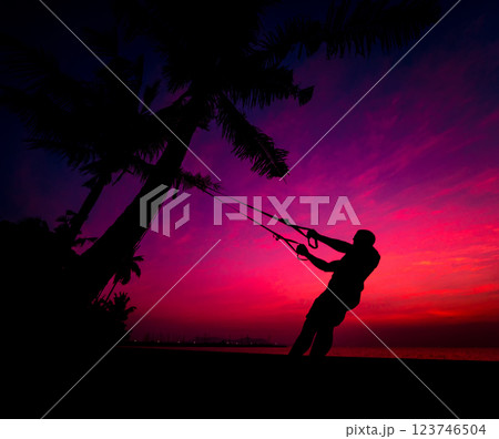 The athlete performs exercises on the beach with fitness straps 123746504