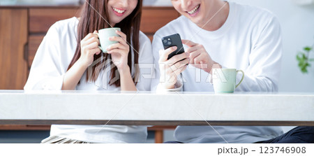リビングでスマホを持って笑顔の男女 リビングでスマホを持って笑顔の男女 123746908