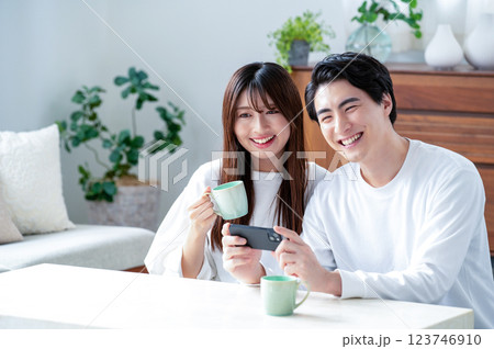 リビングでスマホを持って笑顔の男女 リビングでスマホを持って笑顔の男女 123746910