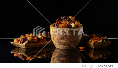 Mix of various nuts and raisins on a black reflective background. 123747841