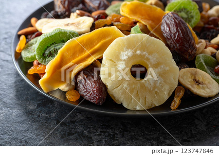 Dried tropical fruits, nuts, and raisins in black plate. Dried tropical fruits, nuts, and raisins in black plate. 123747846