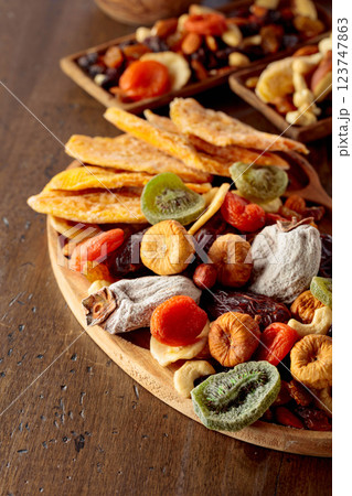 Mix of dried tropical fruits, nuts, and raisins on a wooden table. Mix of dried tropical fruits, nuts, and raisins on a wooden table. 123747863