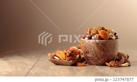 Dried fruits and nuts on a beige ceramic table. 123747877