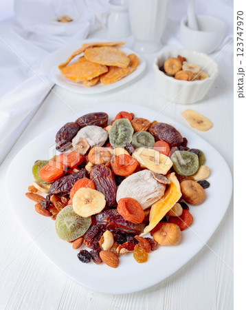 Mix of dried tropical fruits, nuts, and raisins on a white table. Mix of dried tropical fruits, nuts, and raisins on a white table. 123747970