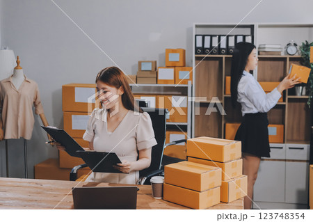 Startup SME small business entrepreneur of freelance Asian woman using a laptop with box Cheerful success Asian woman her hand lifts up online marketing packaging box and delivery SME idea concept 123748354