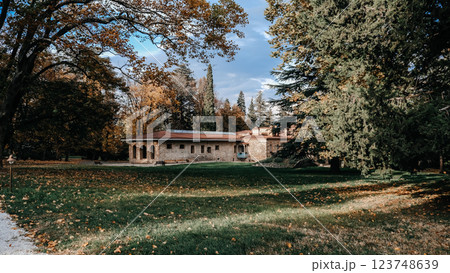 Beautiful and Charming Autumn Landscape Featuring a Rustic House Surrounded by Lush Green Lawn 123748639