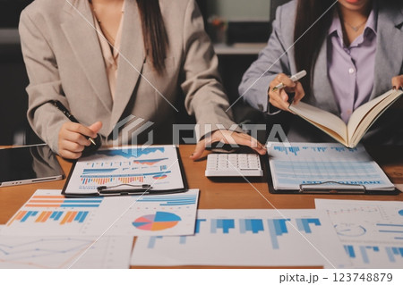 Group of confident business people point to graphs and charts to analyze market data, balance sheet, account, net profit to plan new sales strategies to increase production capacity. Group of confident business people point to graphs and charts to analyze market data, balance sheet, account, net profit to plan new sales strategies to increase production capacity. 123748879