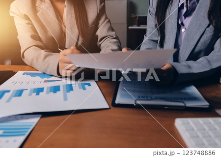 Group of confident business people point to graphs and charts to analyze market data, balance sheet, account, net profit to plan new sales strategies to increase production capacity. 123748886