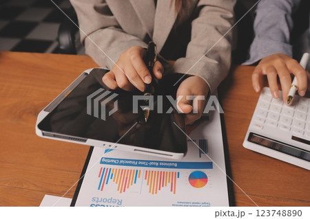 Group of confident business people point to graphs and charts to analyze market data, balance sheet, account, net profit to plan new sales strategies to increase production capacity. Group of confident business people point to graphs and charts to analyze market data, balance sheet, account, net profit to plan new sales strategies to increase production capacity. 123748890