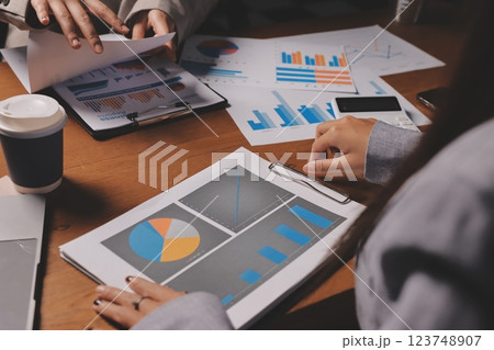 Group of confident business people point to graphs and charts to analyze market data, balance sheet, account, net profit to plan new sales strategies to increase production capacity. 123748907