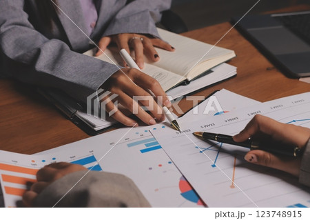 Group of confident business people point to graphs and charts to analyze market data, balance sheet, account, net profit to plan new sales strategies to increase production capacity. 123748915