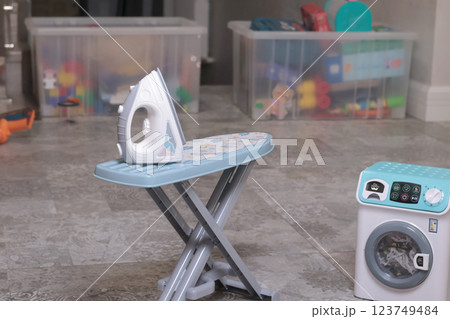 Toy household appliances, iron, ironing table, washing machine at home on floor. Cleaning, household chores, baby and educational games.  123749484