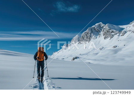 A man is walking in the snow with a backpack on A man is walking in the snow with a backpack on 123749949