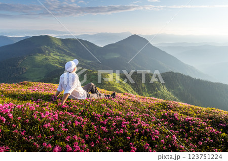 Traveler sitting among blooming rhododendrons Traveler sitting among blooming rhododendrons 123751224