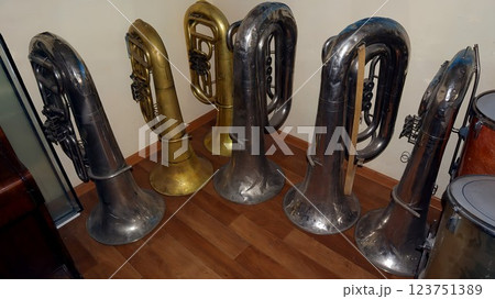 A collection of old brass instruments is arranged in a music school, showcasing various tubas and euphoniums that reflect rich musical heritage and artistry. 123751389