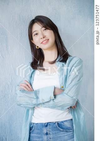 水色背景で笑顔で見上げるカジュアルな服を着た女性　カメラ目線で腕を組む 123751477