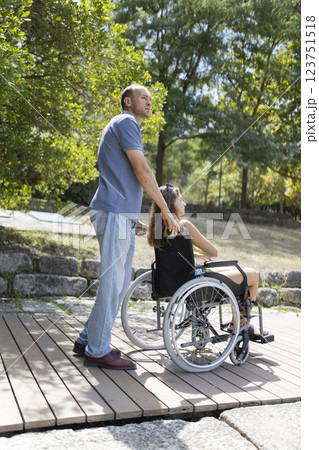 Nurse helping disabled patient enjoying a sunny day in a park Nurse helping disabled patient enjoying a sunny day in a park 123751518