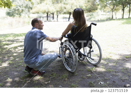 Man assisting woman in wheelchair in park Man assisting woman in wheelchair in park 123751519
