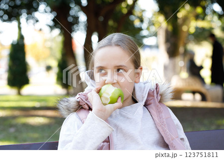 Kid holding green apple. Young girl in park, outdoors portrait 123751811