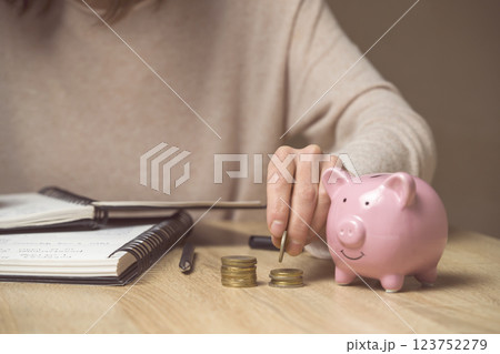 The girl puts her savings in a piggy bank. 123752279