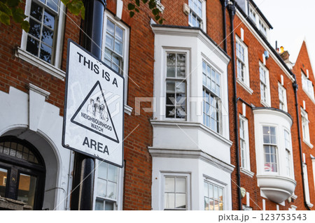 Neighborhood Watch Area Sign on a Pole Framed by Elegant London Brick Homes 123753543