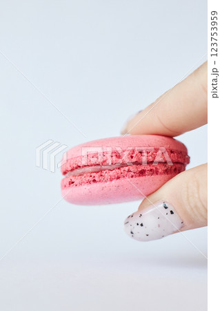 One pink French Macaron in a woman's hand on gray background, berry flavor cake One pink French Macaron in a woman's hand on gray background, berry flavor cake 123753959