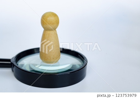 A wooden doll standing on magnifying glass. Representing the chosen one or leadership concept 123753979