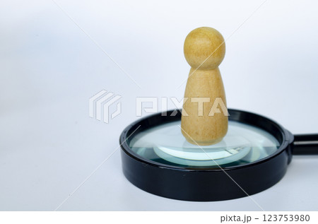 A wooden doll standing on magnifying glass. Representing the chosen one or leadership concept. 123753980