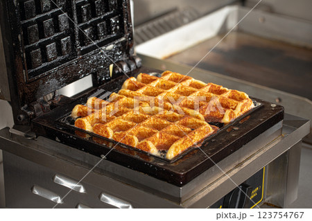 Cooking belgian waffles in the cafe kitchen Cooking belgian waffles in the cafe kitchen 123754767