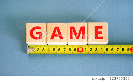 Game symbol. Concept word Game on beautiful wooden blocks. Beautiful yellow ruler. Beautiful blue table blue background. Business, lifestyle and game concept. Copy space. Game symbol. Concept word Game on beautiful wooden blocks. Beautiful yellow ruler. Beautiful blue table blue background. Business, lifestyle and game concept. Copy space. 123755396