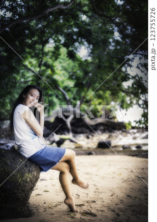 Indonesian girl in a skirt sitting on a stone Indonesian girl in a skirt sitting on a stone 123755726