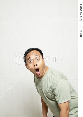 Funny face man wow and OMG. Shocked and surprised face of an Asian man in a sage green shirt isolated on white. 123755964