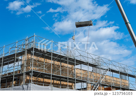 青空と型枠部材を運ぶクレーン 123756103