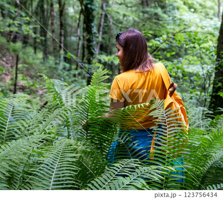 young woman hiking through lush green forest, wearing yellow backpack and T-shirt, explorer enjoying an outdoor adventure in scenic landscape, wilderness exploration, forest therapy, active lifestyles young woman hiking through lush green forest, wearing yellow backpack and T-shirt, explorer enjoying an outdoor adventure in scenic landscape, wilderness exploration, forest therapy, active lifestyles 123756434