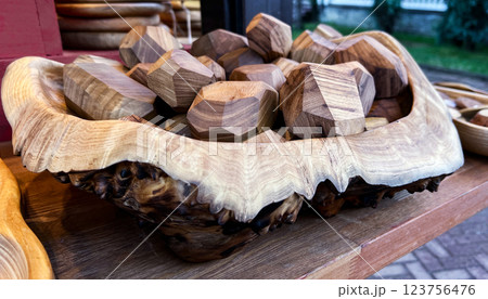 close-up of a rustic wooden bowl filled with handcrafted geometric wooden decorations. The bowl features intricate natural wood grain and textured edges, showcasing exceptional artisanal craftsmanship 123756476